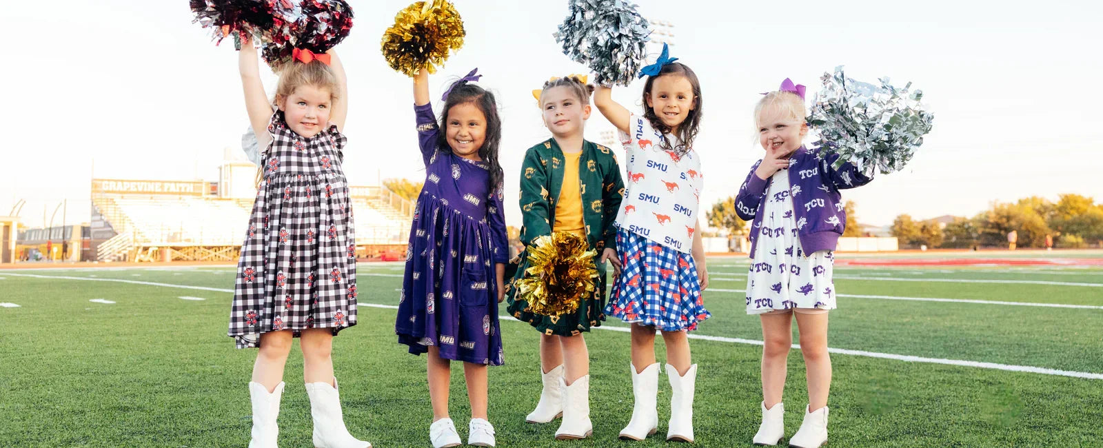 Five young girls in licensed college dresses and white cowboy boots holding pom-poms on a football field.