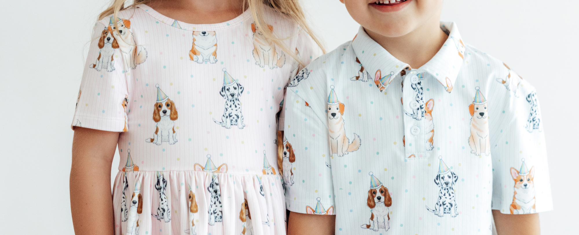 Children wearing matching pastel outfits featuring a playful party dog print with polka dots.