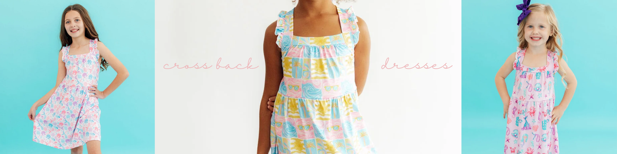 Girls wearing colorful summer-themed ruffle dresses with cross-back straps.