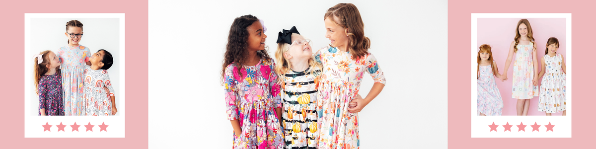 Three young girls smiling in colorful, patterned twirl dresses with floral and seasonal prints against a white background.