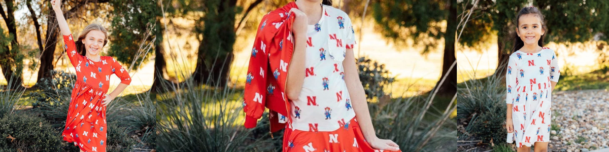 Children wearing red and white University of Nebraska Cornhuskers dresses and jackets featuring Herbie Husker prints.