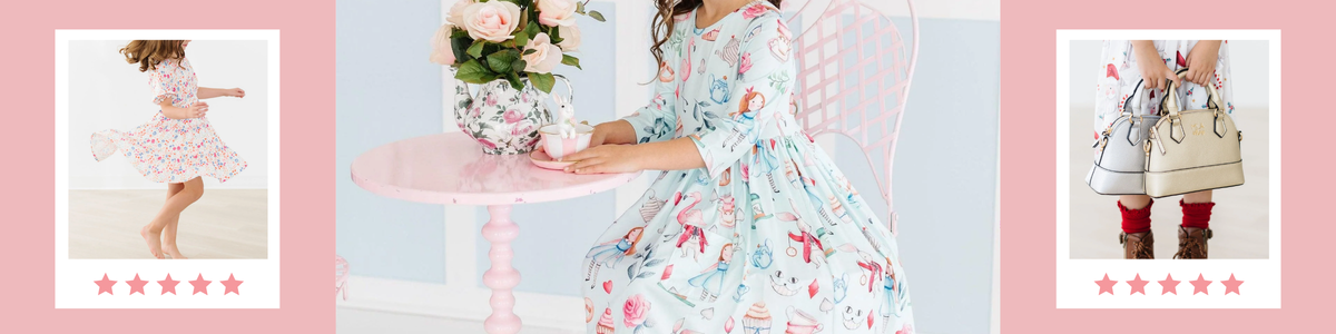 Young girl in a whimsical Alice in Wonderland print dress sitting at a pink tea table with floral decor.