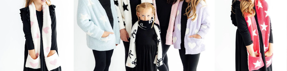Group of children wearing cozy, plush knit scarves and cardigans featuring star, heart, and bow patterns.